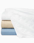 Palatino quilt in white, sand and sea stacked and folded on a white background.