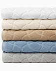 Oasi bath towels stacked from top to bottom in white, ivory, sand, sea and platinum.