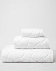 Oasi white bath towels side view stacked, top to bottom: washcloth, hand towel, bath towel.