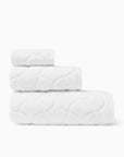 Oasi white bath towel, hand towel, and wascloth folded and stacked side view
