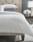 Corner image of a grey SFERRA Abriana Duvet Cover with pillows and shams.