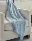SFERRA Palmilla throw in blue draped over a beige armchair.