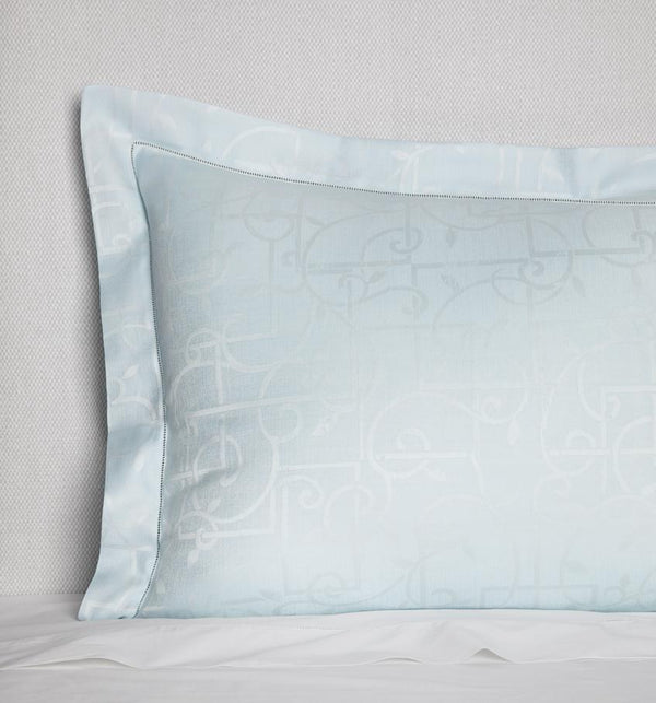 Corner shot of a light blue sateen sham woven with a white trellis pattern against a white background.
