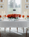 A table with orange flowers set with the SFERRA Classico fine linen table collection.