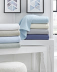 The SFERRA Corino lightweight, breathable cotton blanket in white, ivory, seagreen, and powder blue.