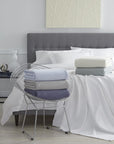 The SFERRA Corino lightweight, breathable cotton blanket in white, ivory, seagreen, and powder blue.