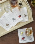 SFERRA Insetti cocktail napkins feature endearing insects on white hemstitched linen napkins.