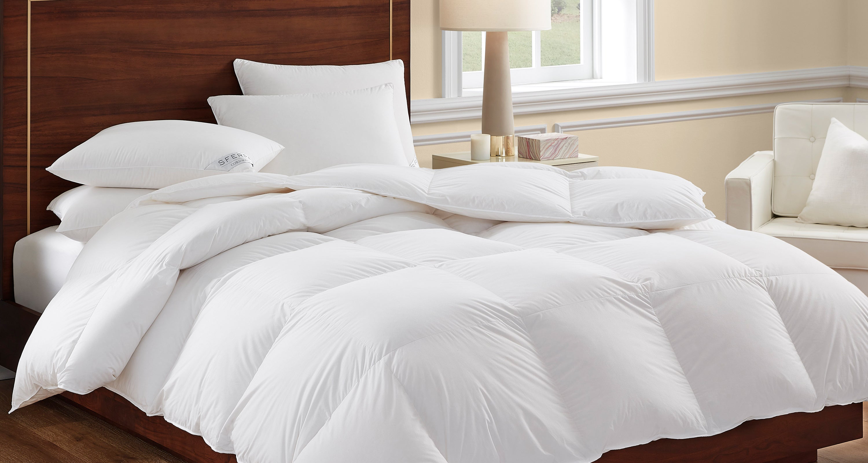A SFERRA white goose down duvet draped over a bed.