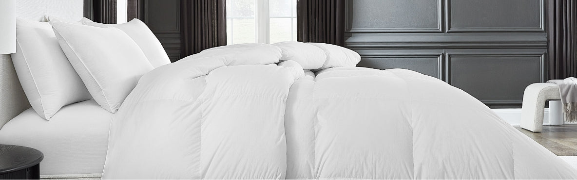 A SFERRA white goose down duvet draped over a bed.