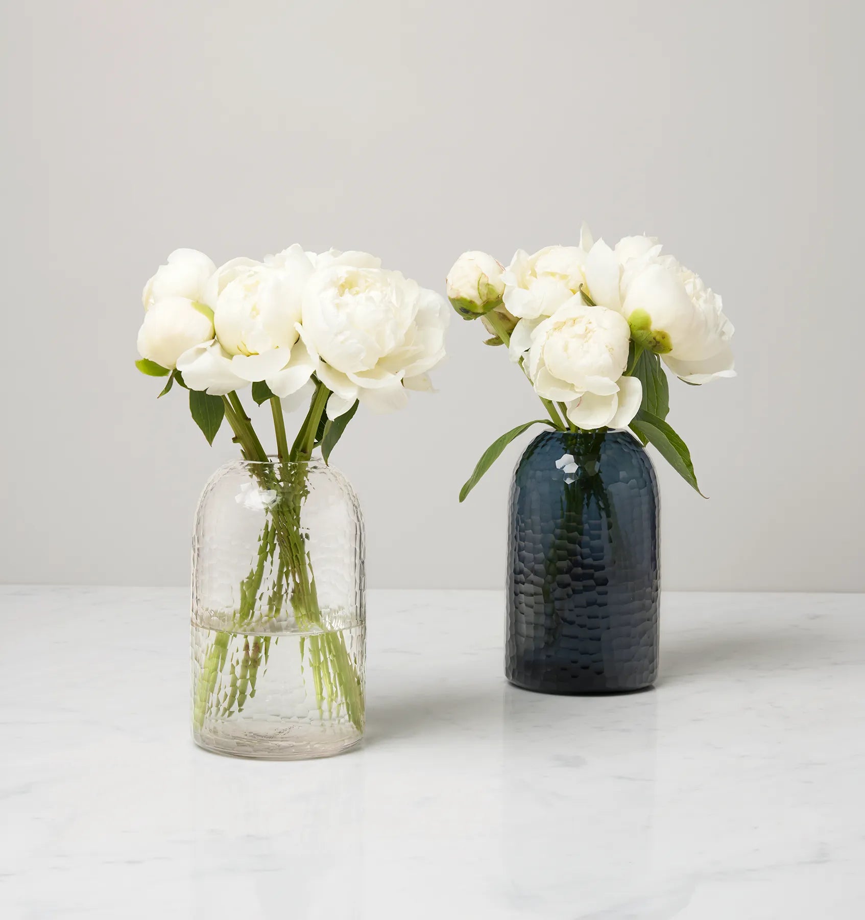 Oculus vase in clear and smoke filled with white flowers