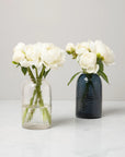 Oculus vase in clear and smoke filled with white flowers