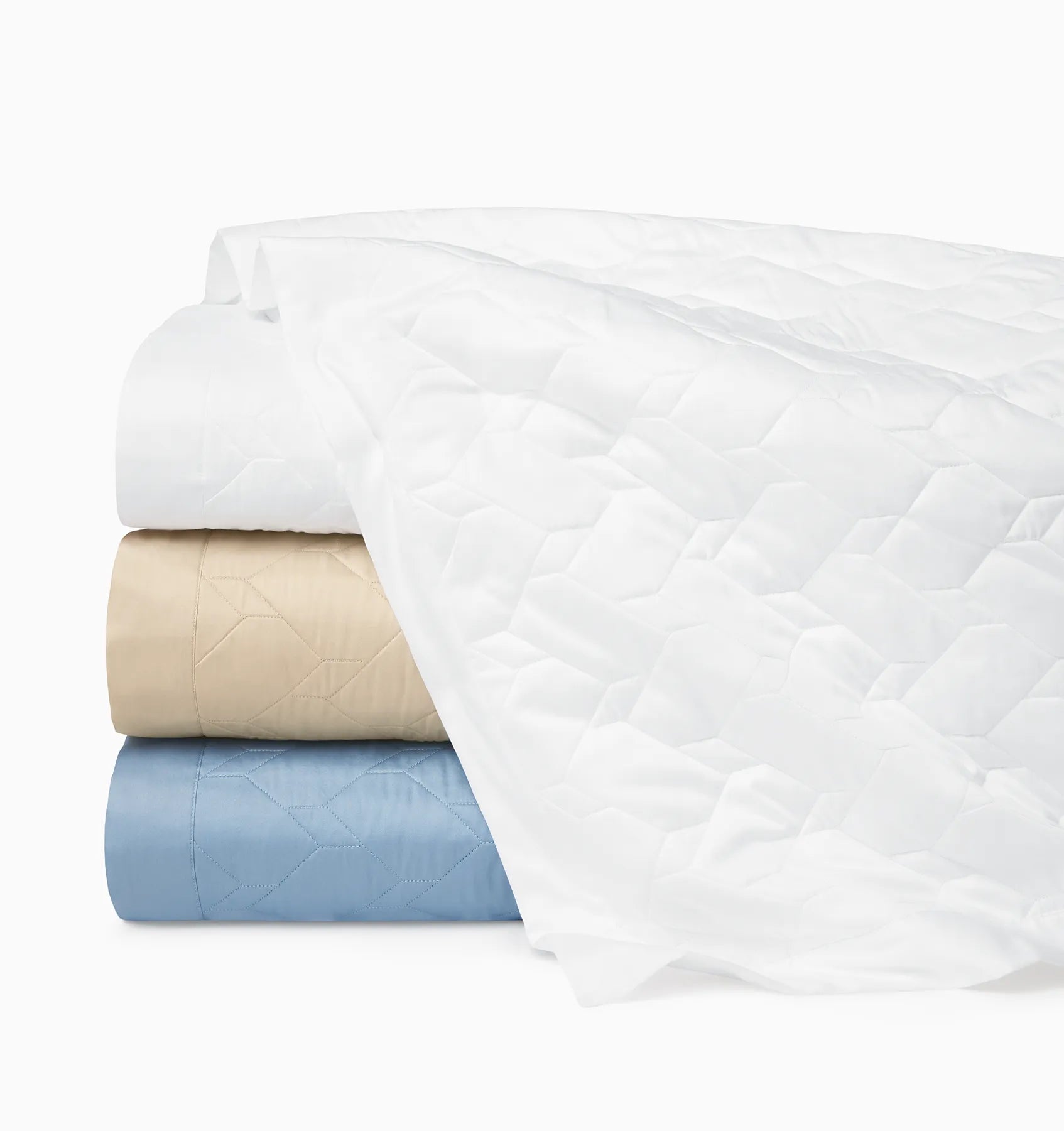 Palatino quilt in white, sand and sea stacked and folded on a white background.