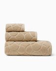 Oasi sand bath towel, hand towel, and wascloth folded and stacked side view
