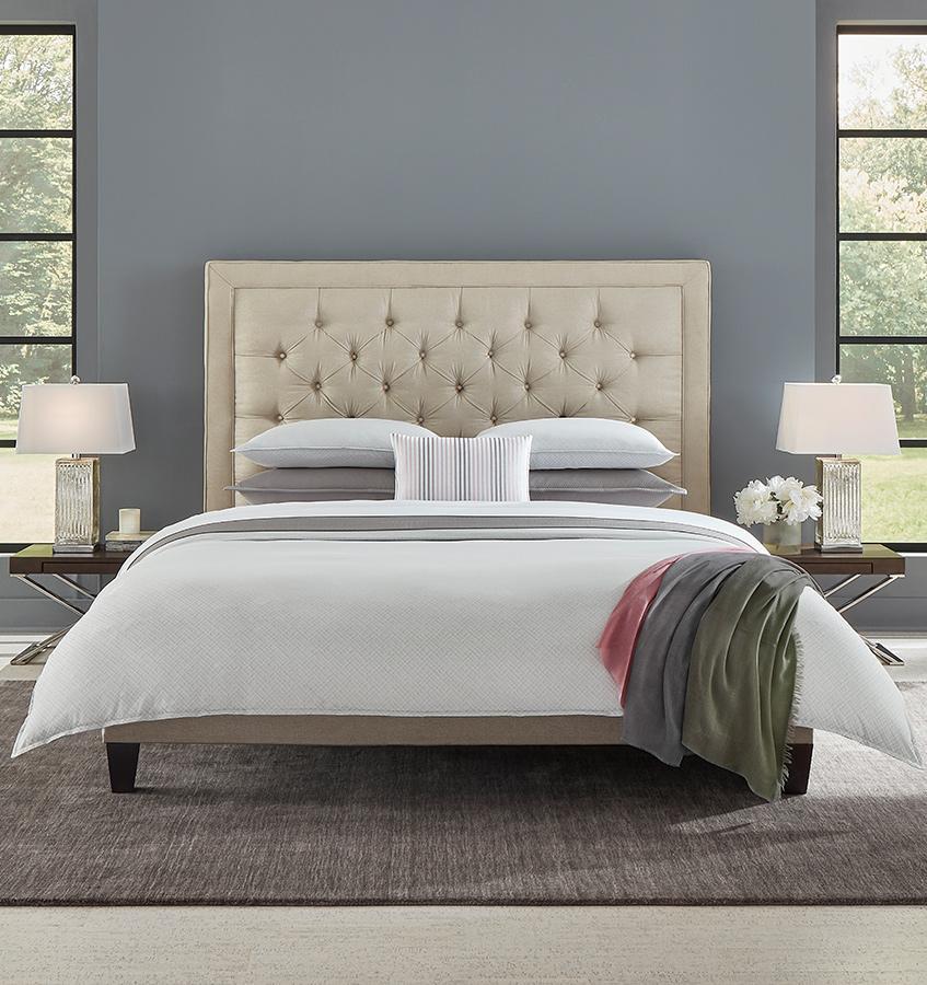 A queen size bed with a grey SFERRA Abriana Duvet Cover, pillows, shams, and a multi-colored throw.