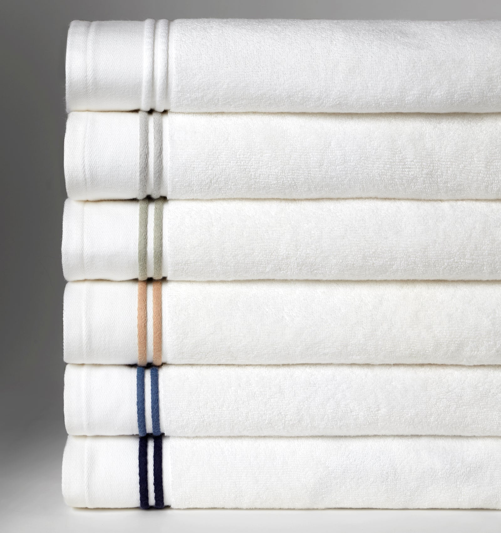 A stack of SFERRA Aura bath towels with multi-colored embroidered striped borders.
