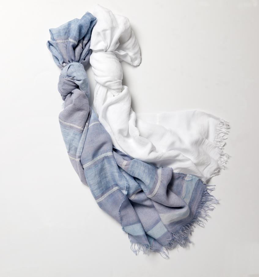 Two SFERRA Garda Scarves in white and blue lied out across a white background.