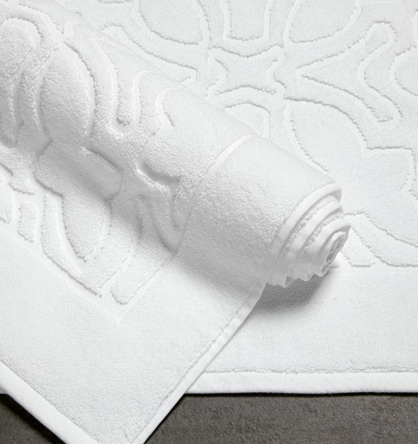 Sculpted jacquard cotton SFERRA Moresco Tub Mat rolled up againsta Moresco Towel.