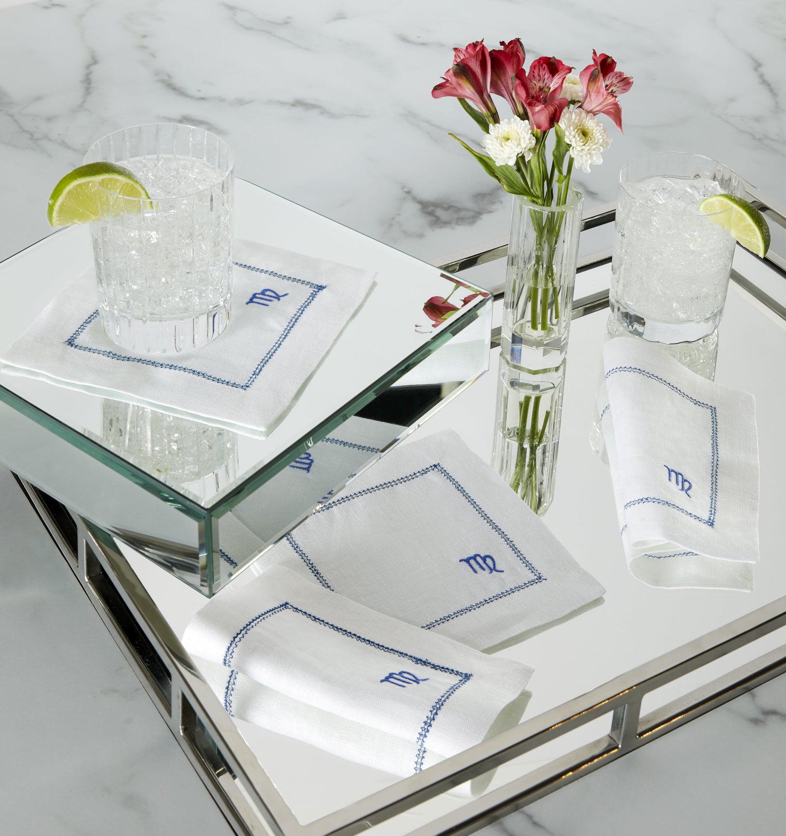 SFERRA linen cocktail napkins featuring Zodiac sign embroidery in a mirrored tray.