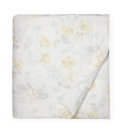White quilted cotton quilt with a light yellow floral motif against a white background.