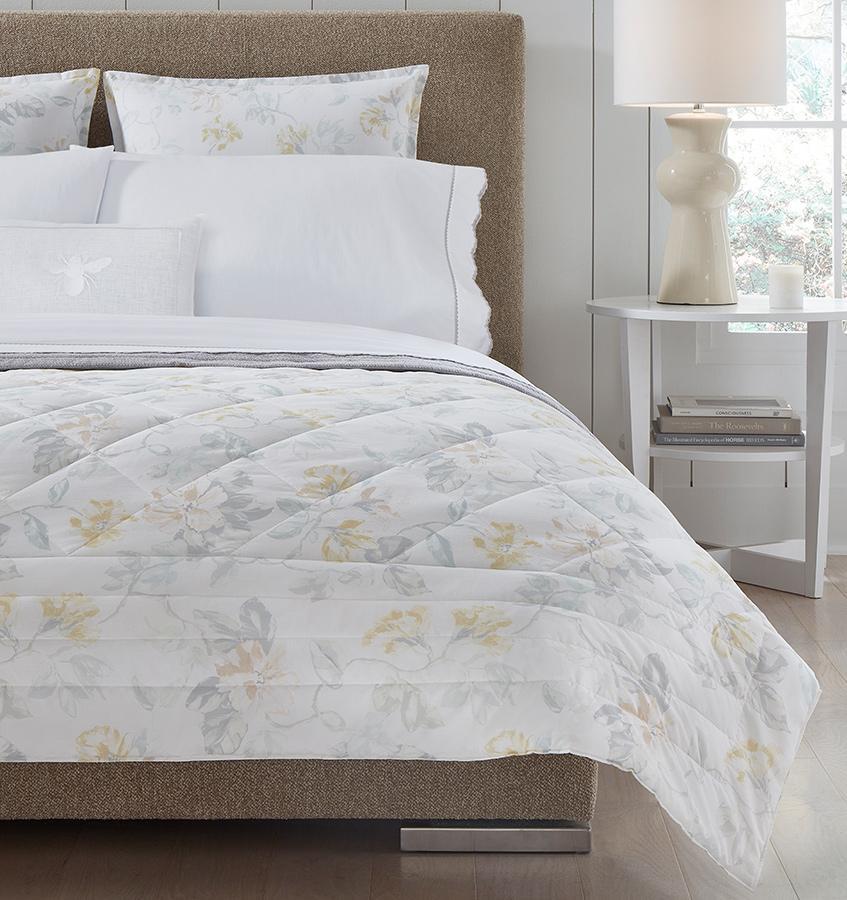 Brown bed with white quilted cotton bedding with a light yellow floral motif.