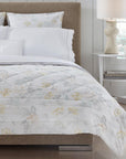 Brown bed with white quilted cotton bedding with a light yellow floral motif.