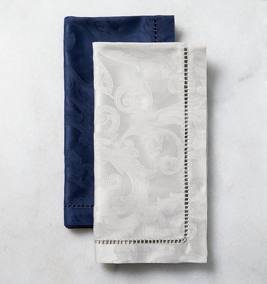 SFERRA Acanthus dinner napkins with a floral pattern laid out against a marble background.