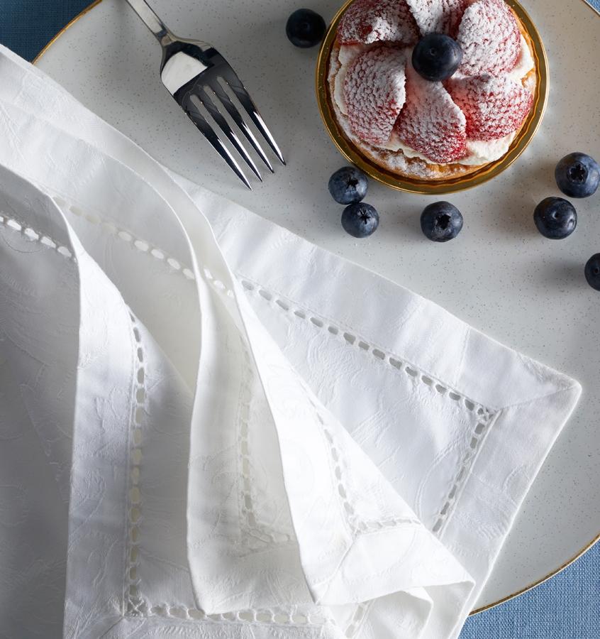 SFERRA Acanthus napkins are jacquard-woven onto fine, long-staple cotton for an elegant, all-over pattern. A blueberry tart with scattered blueberries sits next to the napkins.