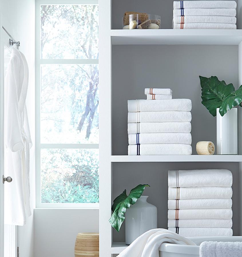 Stacks of SFERRA Aura bath towels with multi-colored embroidered striped borders.