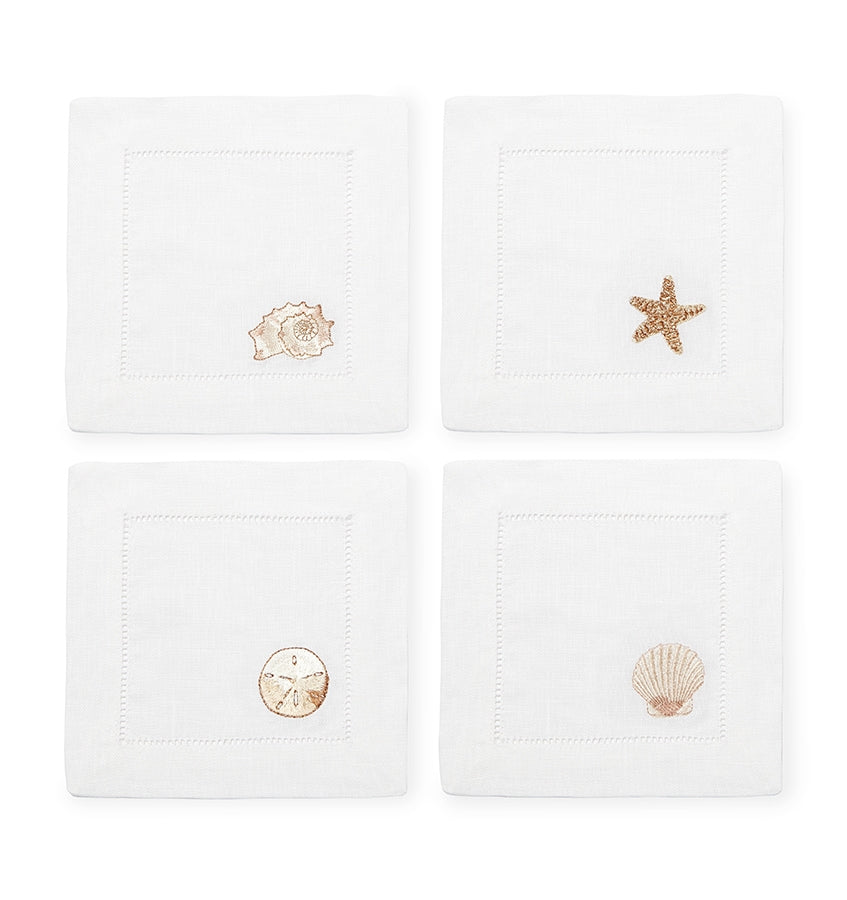SFERRA Beachcomber cocktail napkins feature four delightful seashell embroideries in golden hues on hemstitched linen napkins.