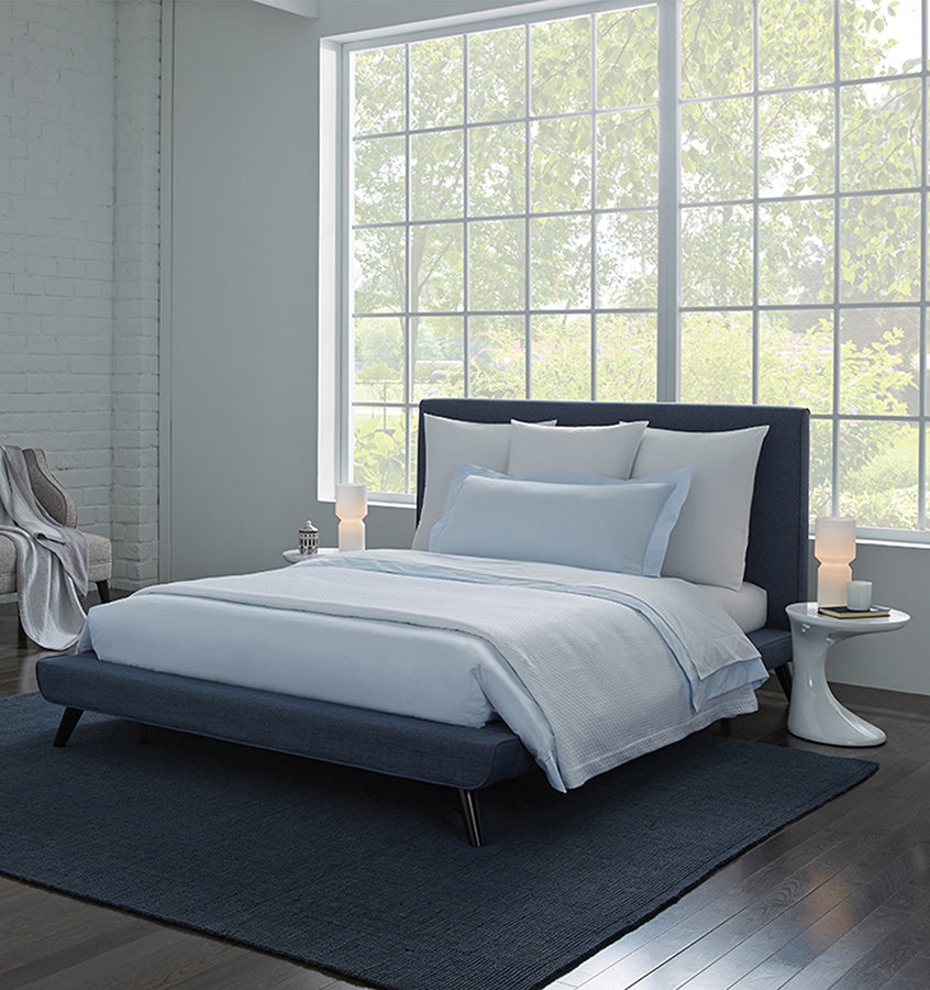 A bed with SFERRA Celeste percale bedding, woven in Italy from pure, extra-long-staple cotton for a super soft hand.