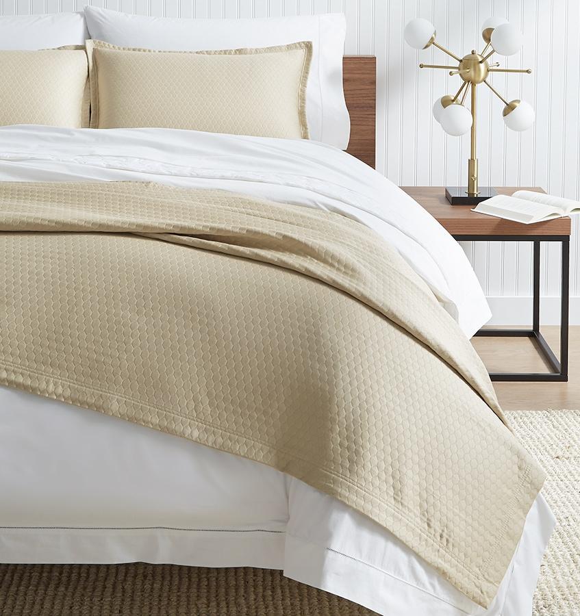 SFERRA Favo Coverlet in beige with a honeycomb pattern.