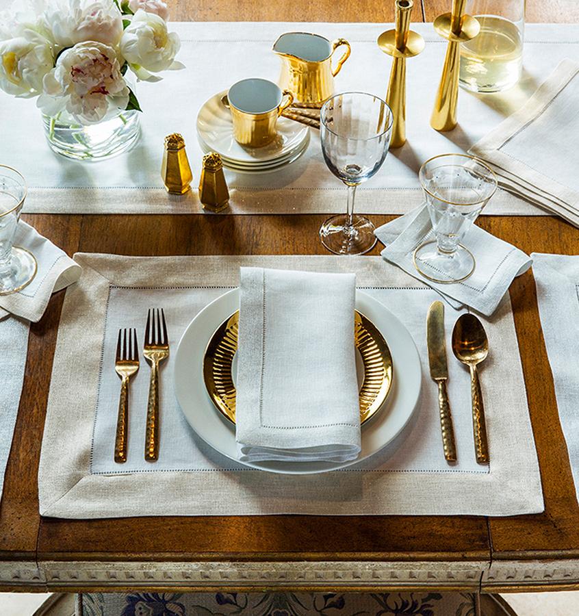 A fall tablescape featuring SFERRA Filetto table linens and gold serveware accents.
