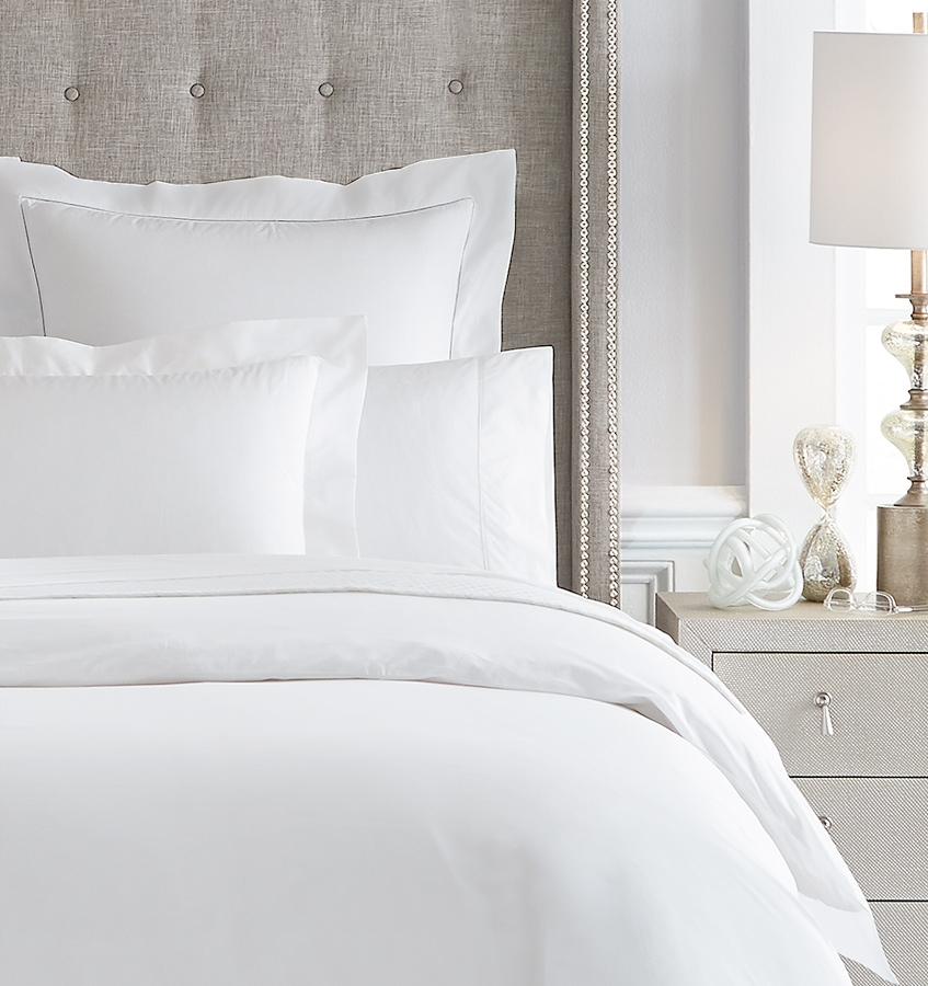 An all-white bed with SFERRA Giza 45 Percale bedding, grown in the Nile river valley, woven by master craftsmen in Italy, and made of the finest cotton in the world.