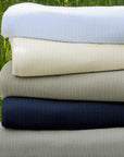 The SFERRA Grant classic cotton blanket in white, ivory, grey, and navy.