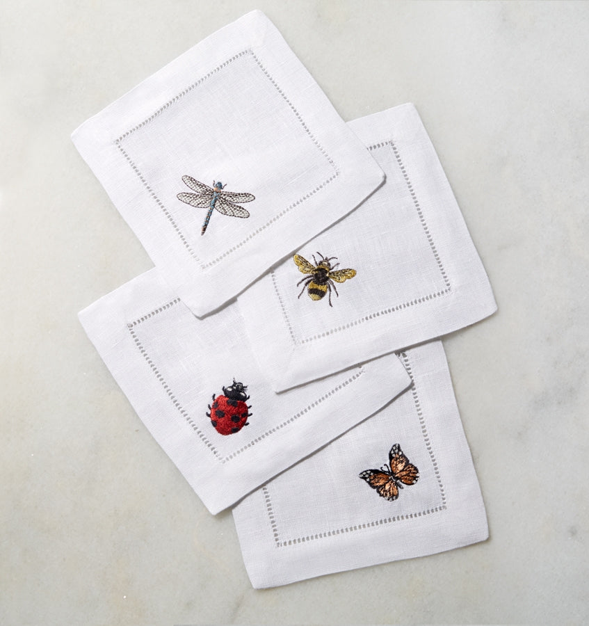 SFERRA Insetti cocktail napkins feature endearing insects on white hemstitched linen napkins.