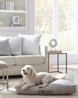 A dog sitting on the monogrammed SFERRA Lettino Dog Bed.